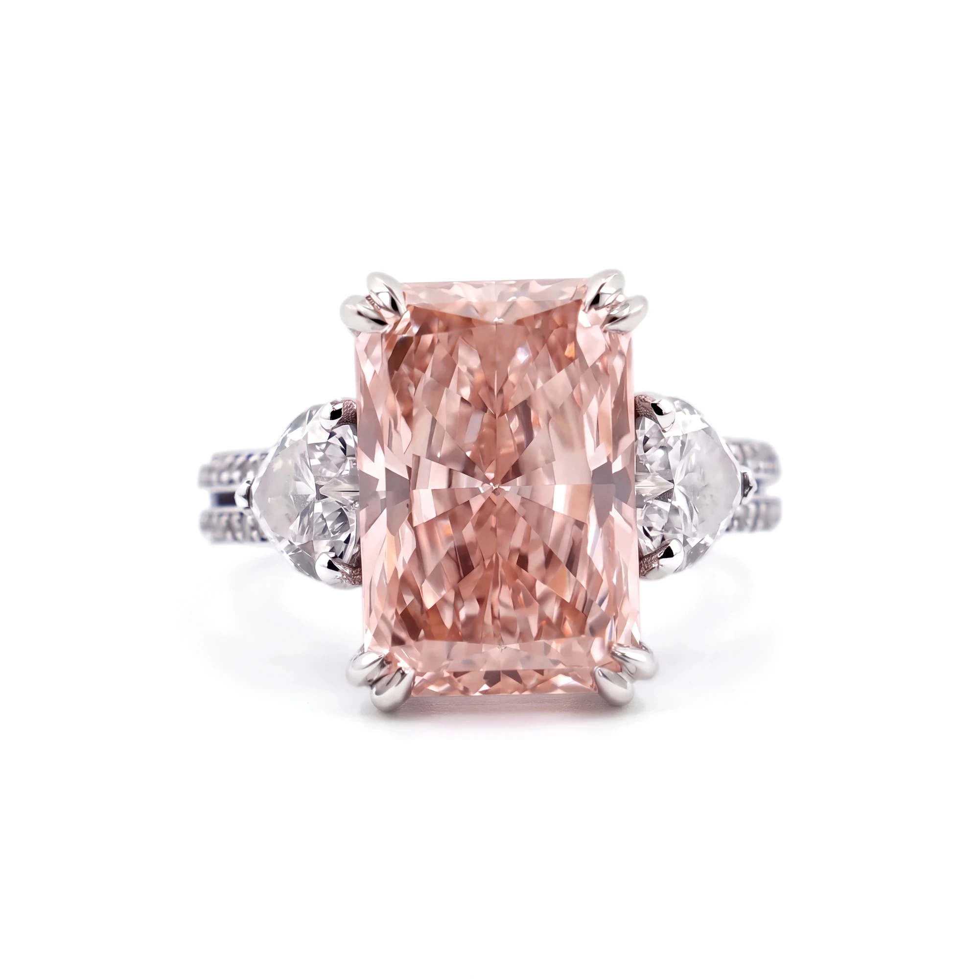 Packshot of a pink radiant-cut diamond ring flanked by two white heart-shaped diamonds, on pure white
